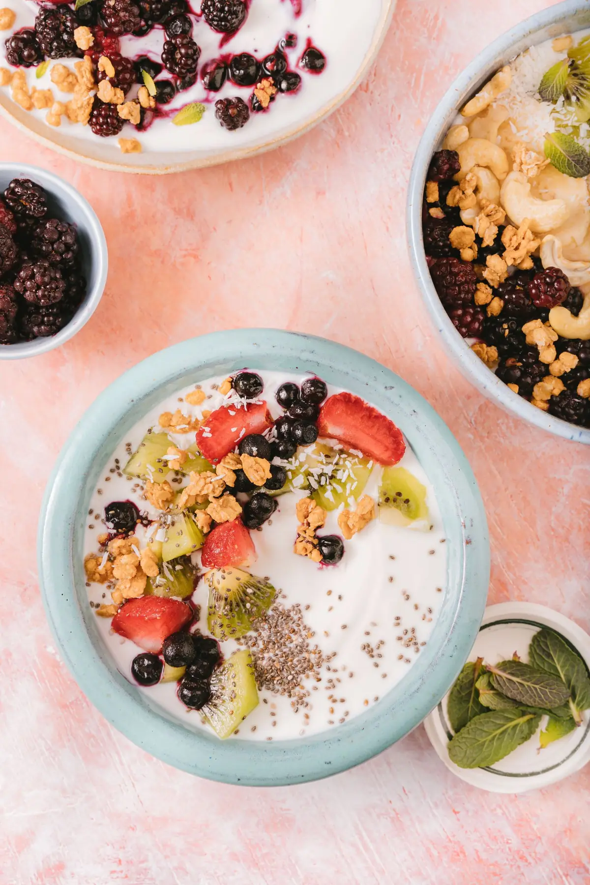 A bowl of yoghurt topped with berries and seeds, with a spoon